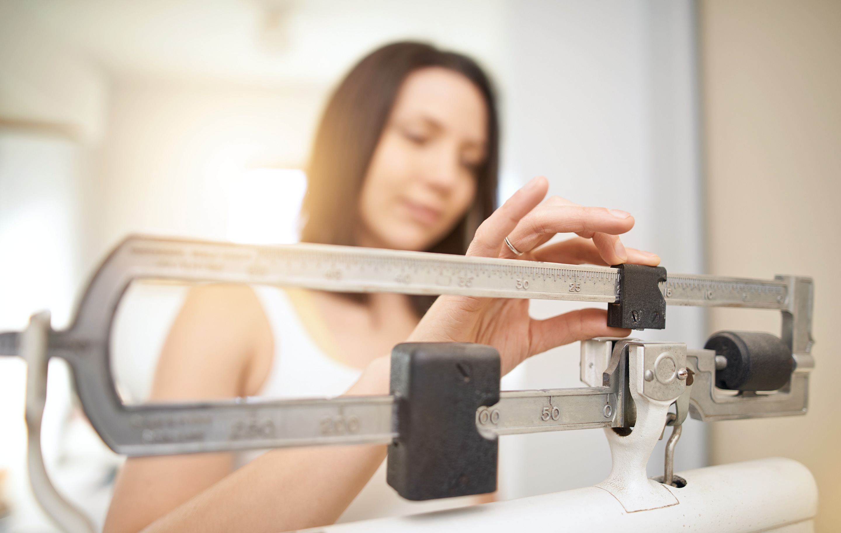 A woman in a softly lit room adjusts a traditional metal scale