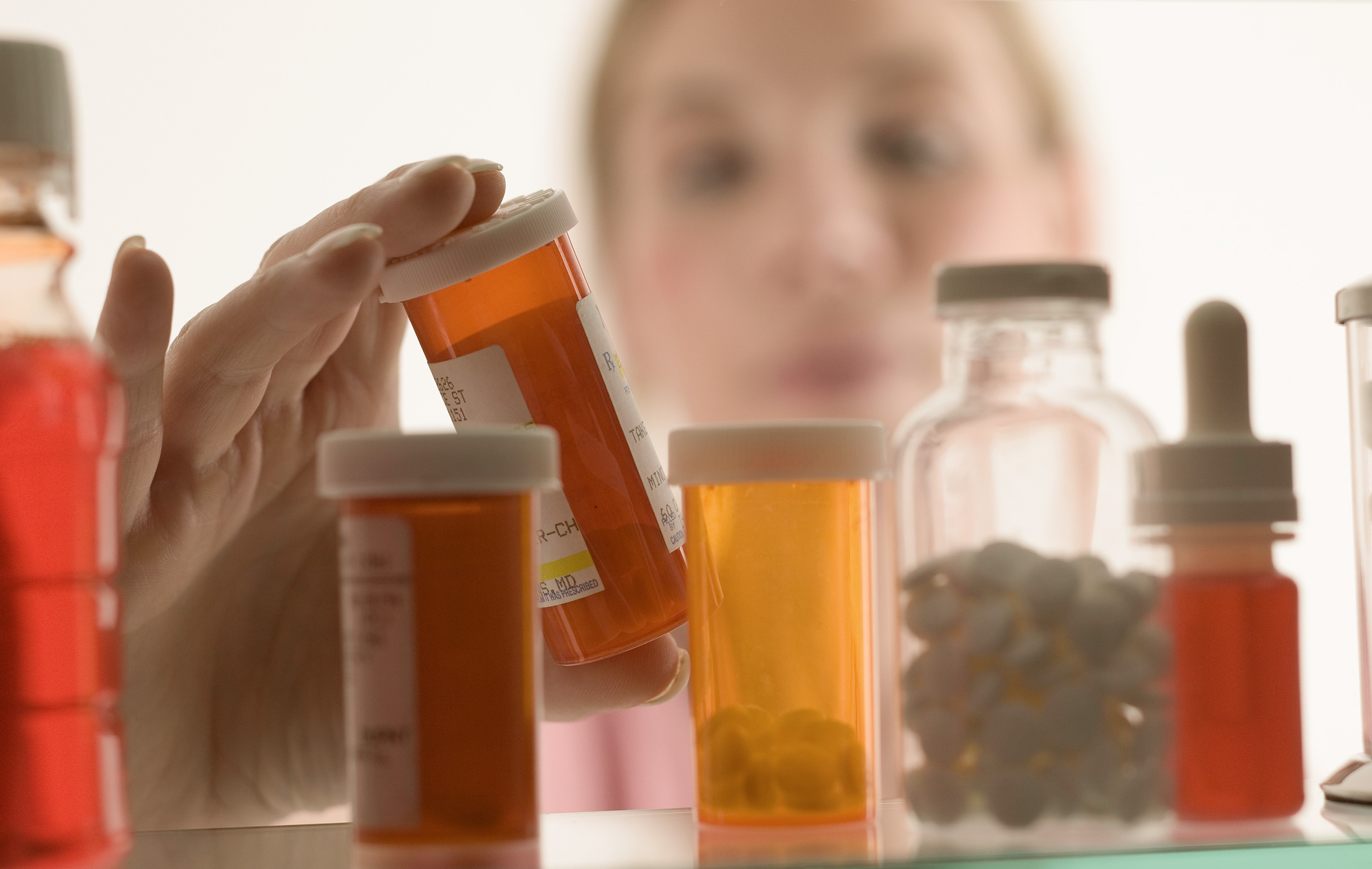Woman gazing into a crowded medicine cabinet