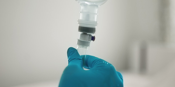 Gloved hand preparing medication for infusion