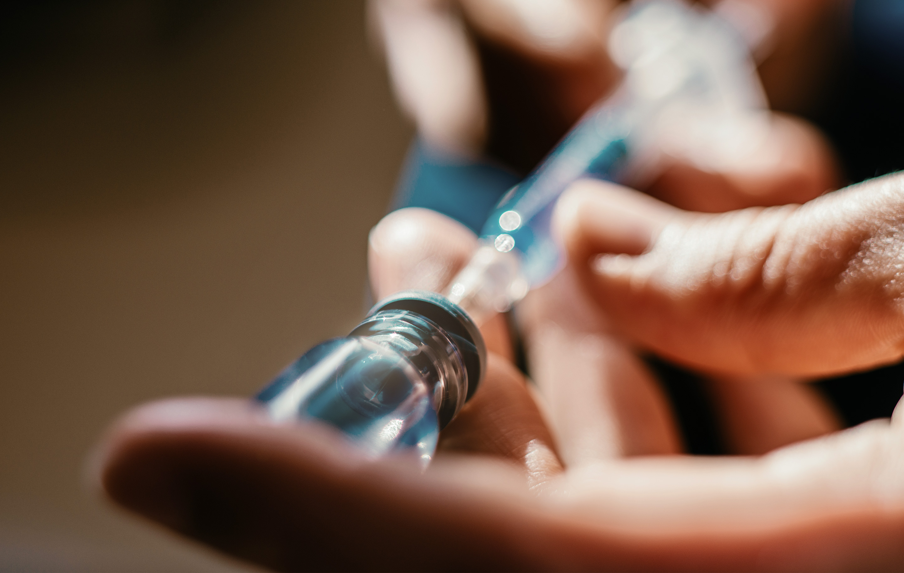 Close-up of hands preparing an injection with syringe and vial