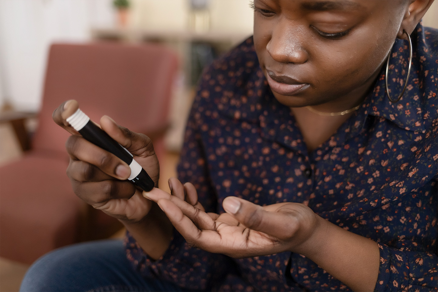 Woman checks blood sugar with glucose meter in home setting, focused and calm expression
