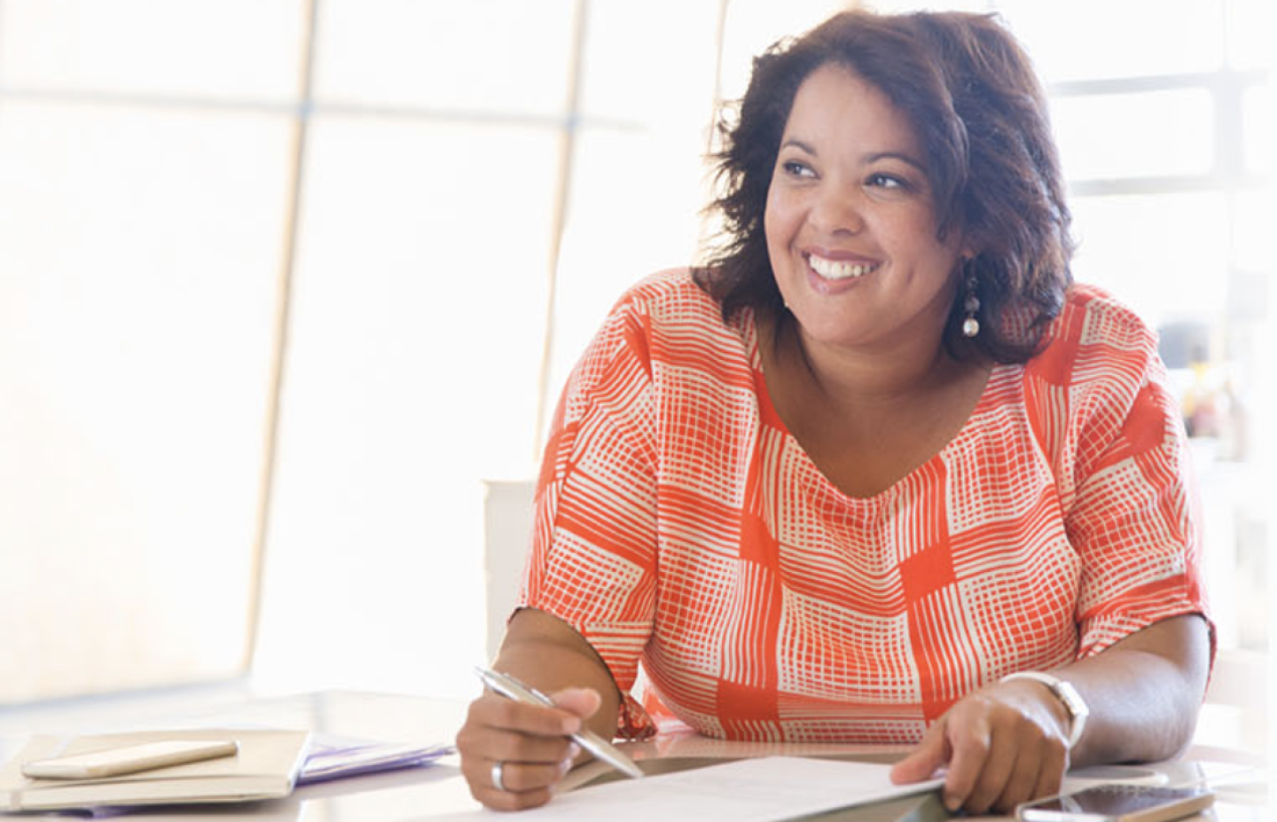 Woman smiles facing left wears orange blouse