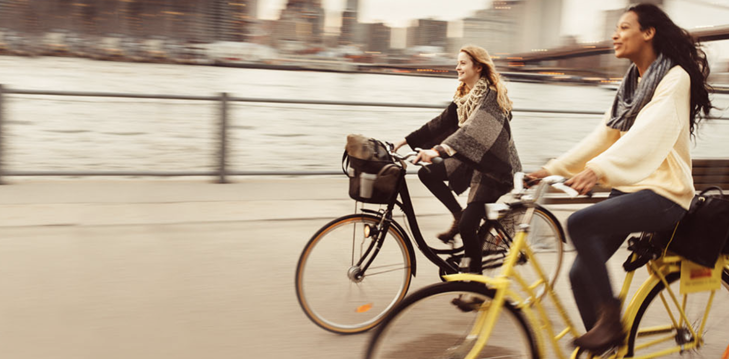 Two women ride bicycles