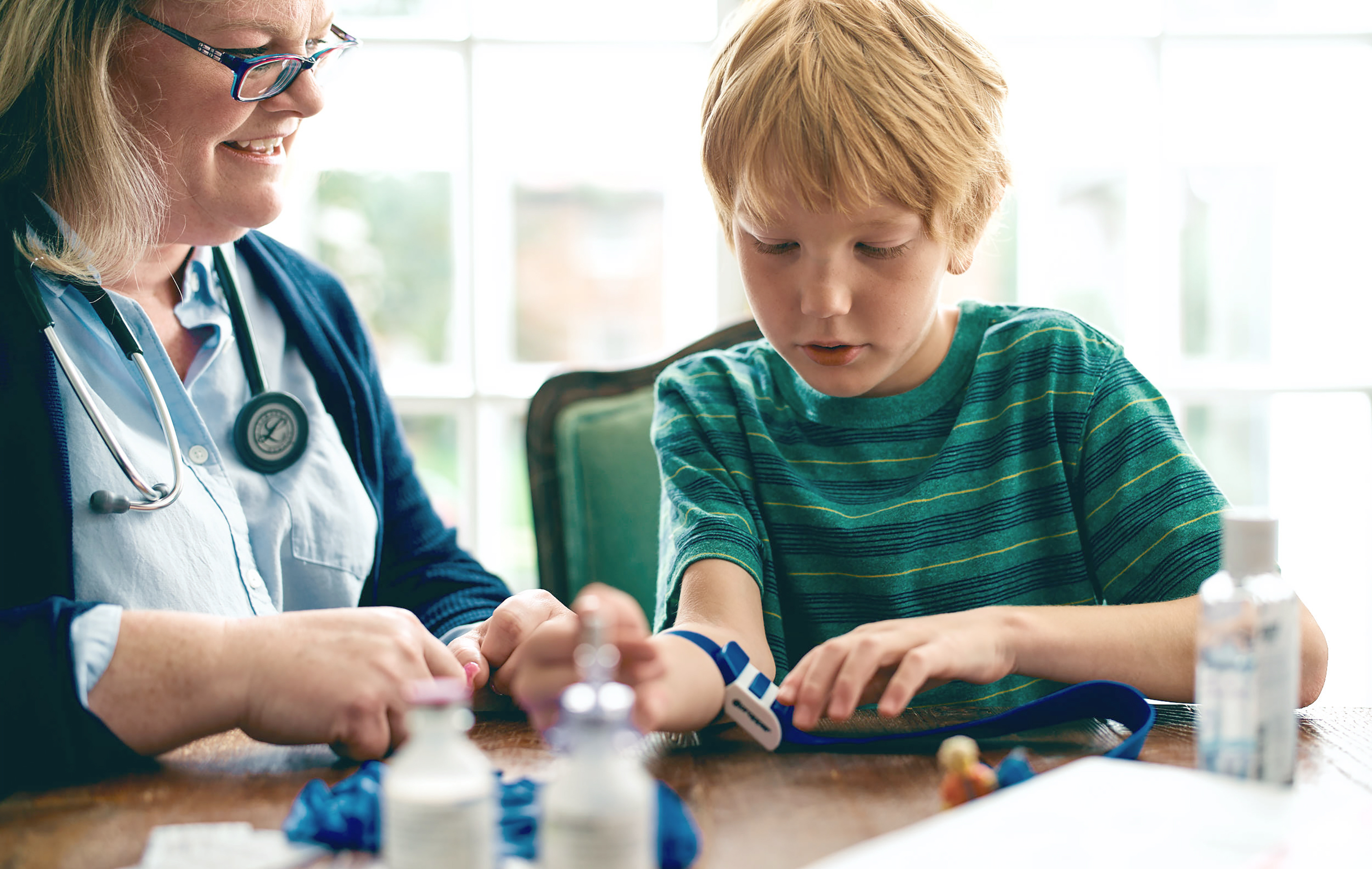 A healthcare provider assists a young boy with a blood pressure cuff on his arm.