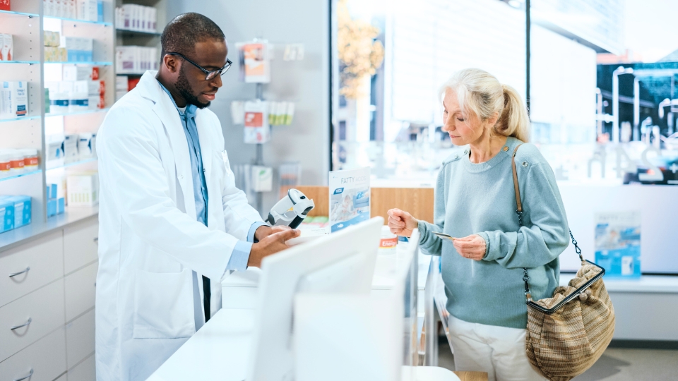 Pharmacist assists customer at counter as she holds product, both focused on selection process.