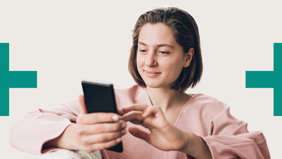 Woman smiling while using smartphone against plain background with teal plus symbols on either side