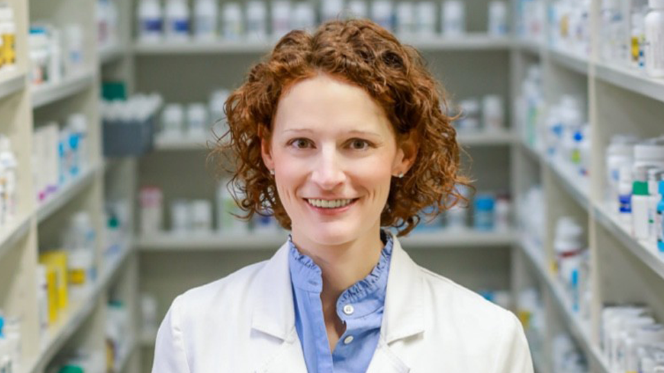 Image of Dr. Stephanie Smith Cooney standing in a pharmacy wearing a lab coat