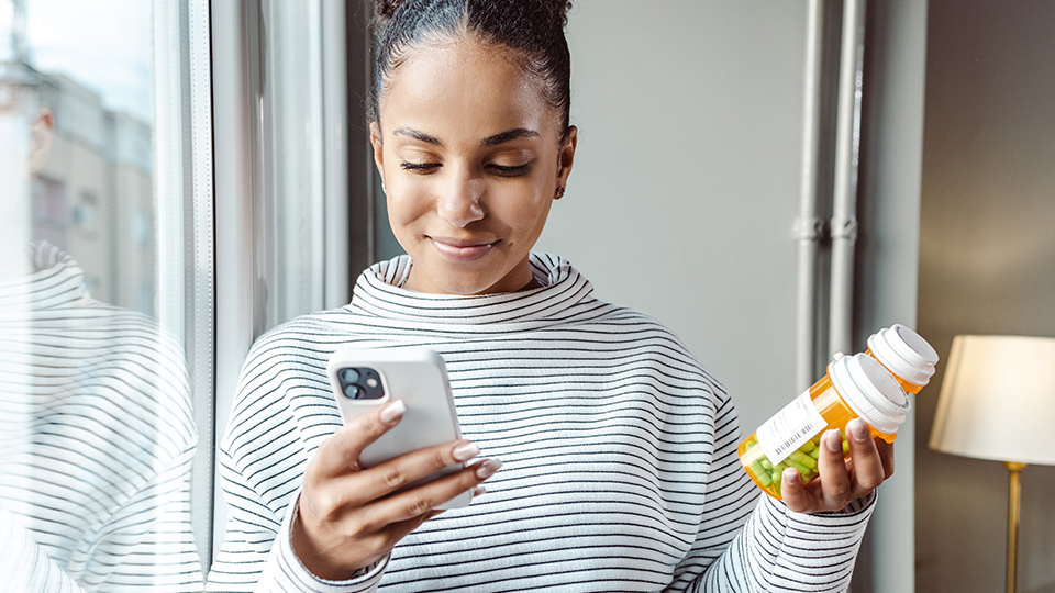 Woman looking at phone and medication