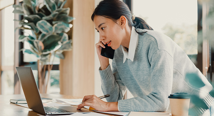 Woman on phone looking at laptop