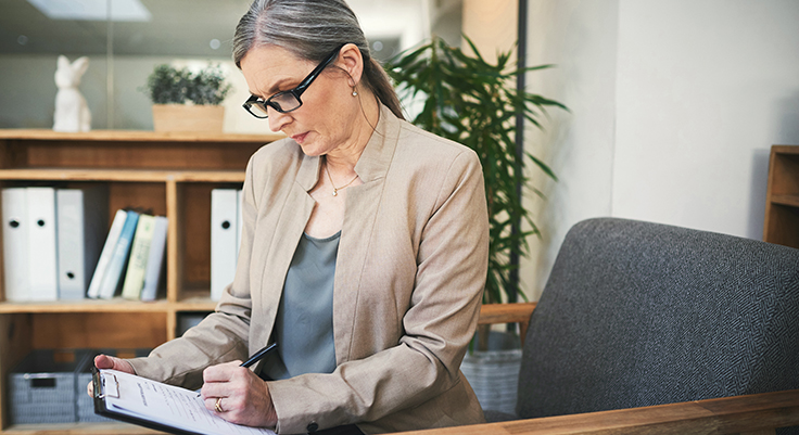 Woman looks down and fills out checklist on clipboard