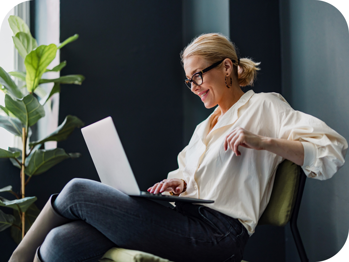 Woman with eyeglasses smiling looking at laptop