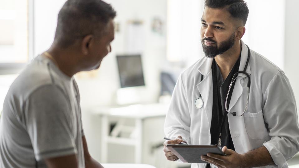 Young bearded doctor talking to elder patient