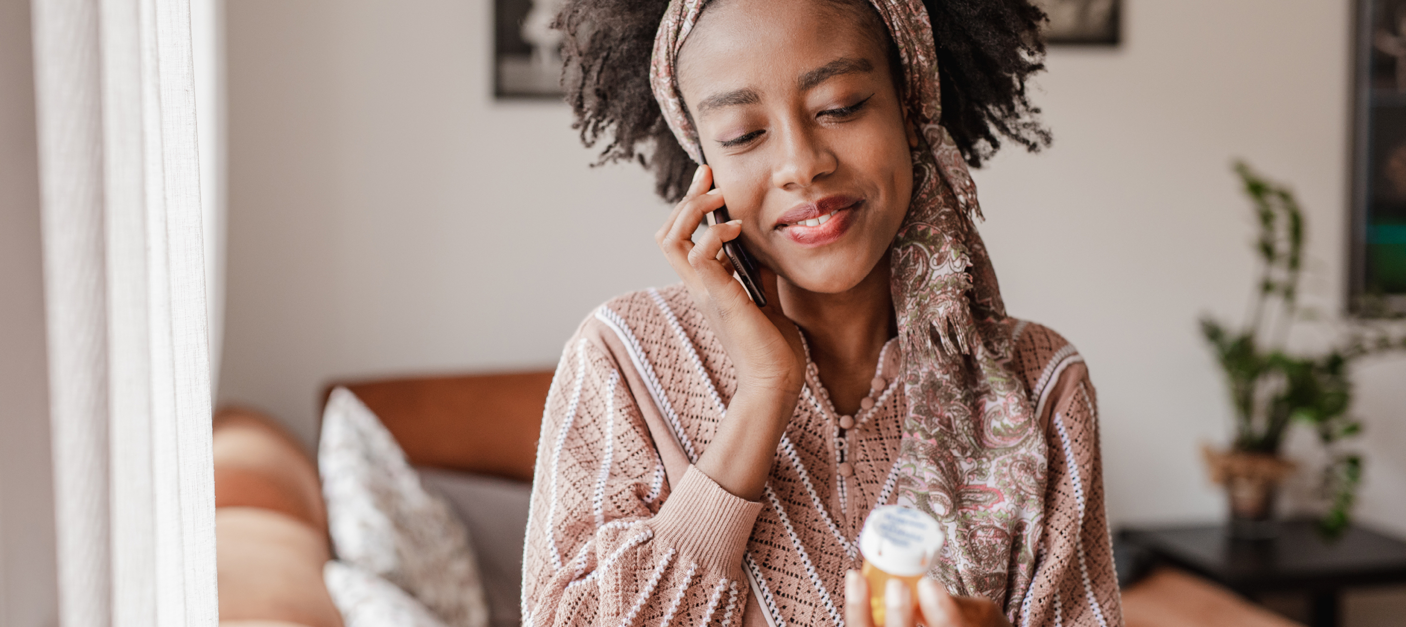 Woman smiling while holding a small pill container.