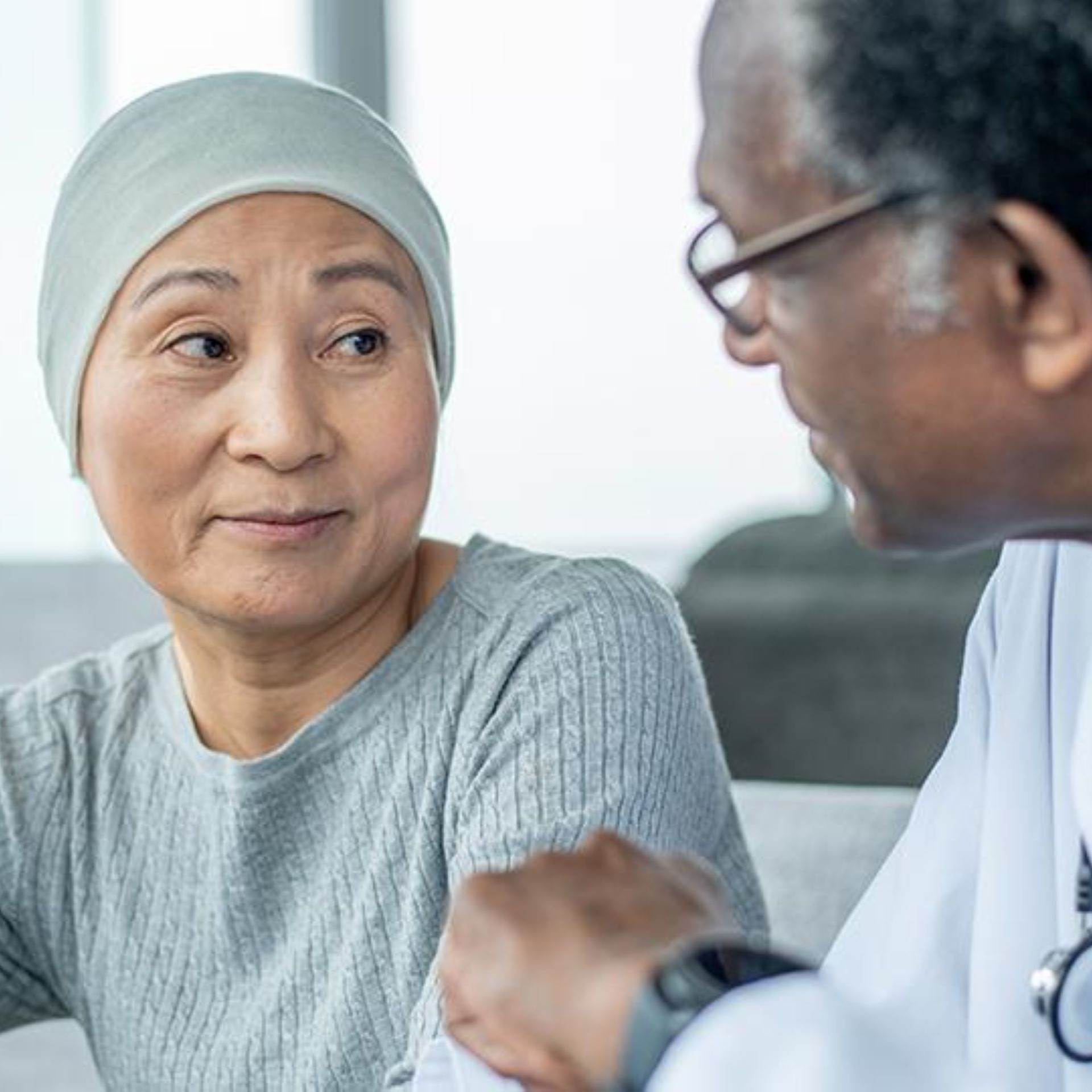 A woman wearing a headscarf sits with a doctor, engaged in a conversation.
