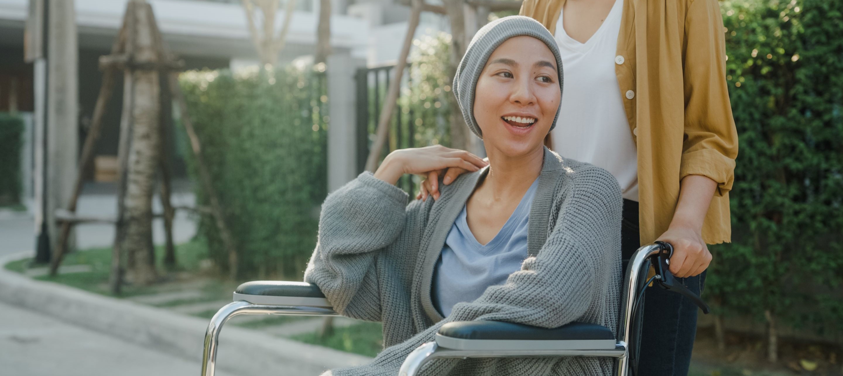 Woman pushing wheelchair with smiling face.