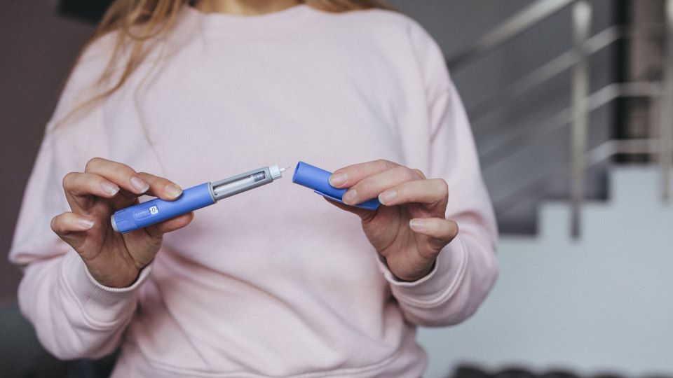 Hand holding blue injector 