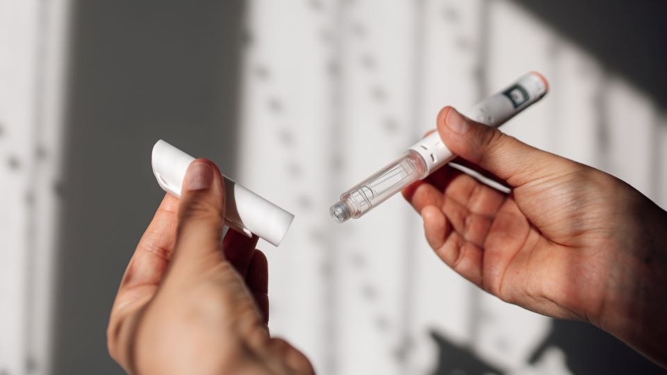 A hands holding a white injector pen