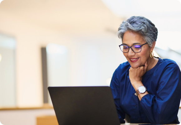 Woman with glasses sits at laptop