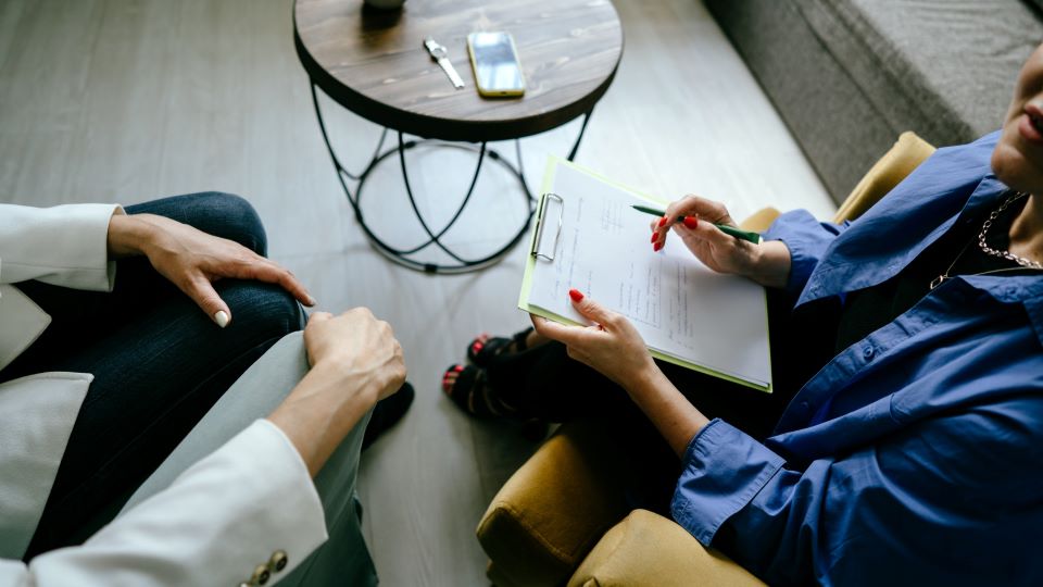 A man and woman are sitting on a couch with a table between them