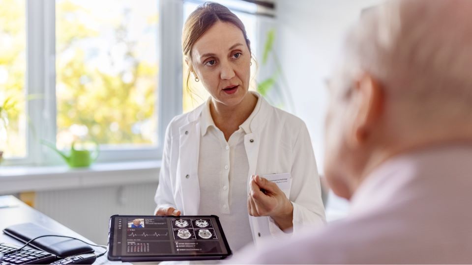 Healthcare professional showing tablet screen to older patient