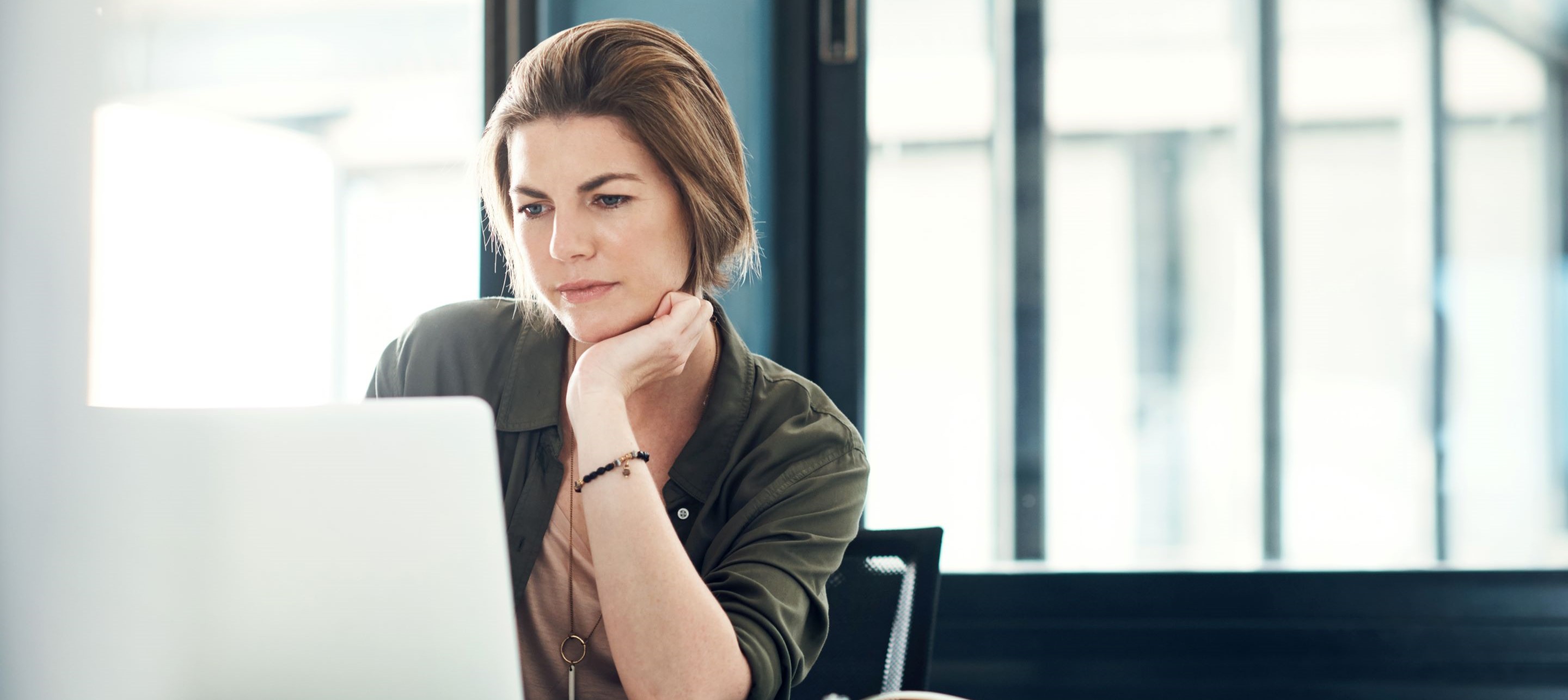 Woman at a desk, looking intently at her laptop.