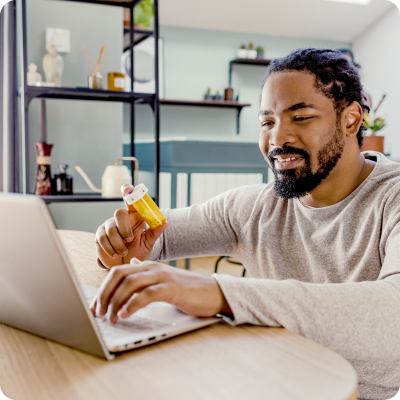 Man with laptop and pill bottle