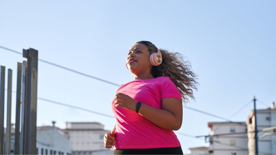 Woman with pink shirt and headphones running