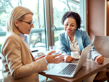 two women at laptop with coffee