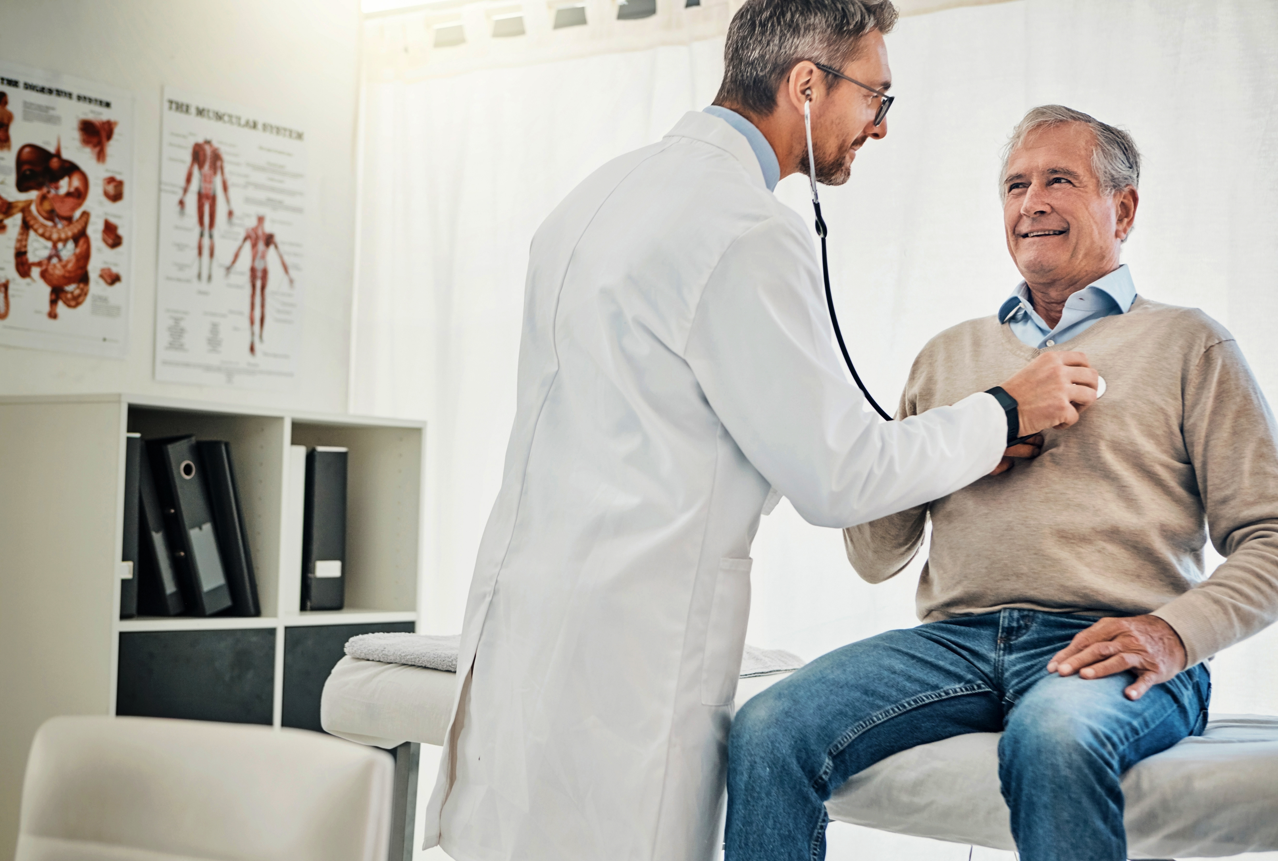 doctor examining elderly man on exam table