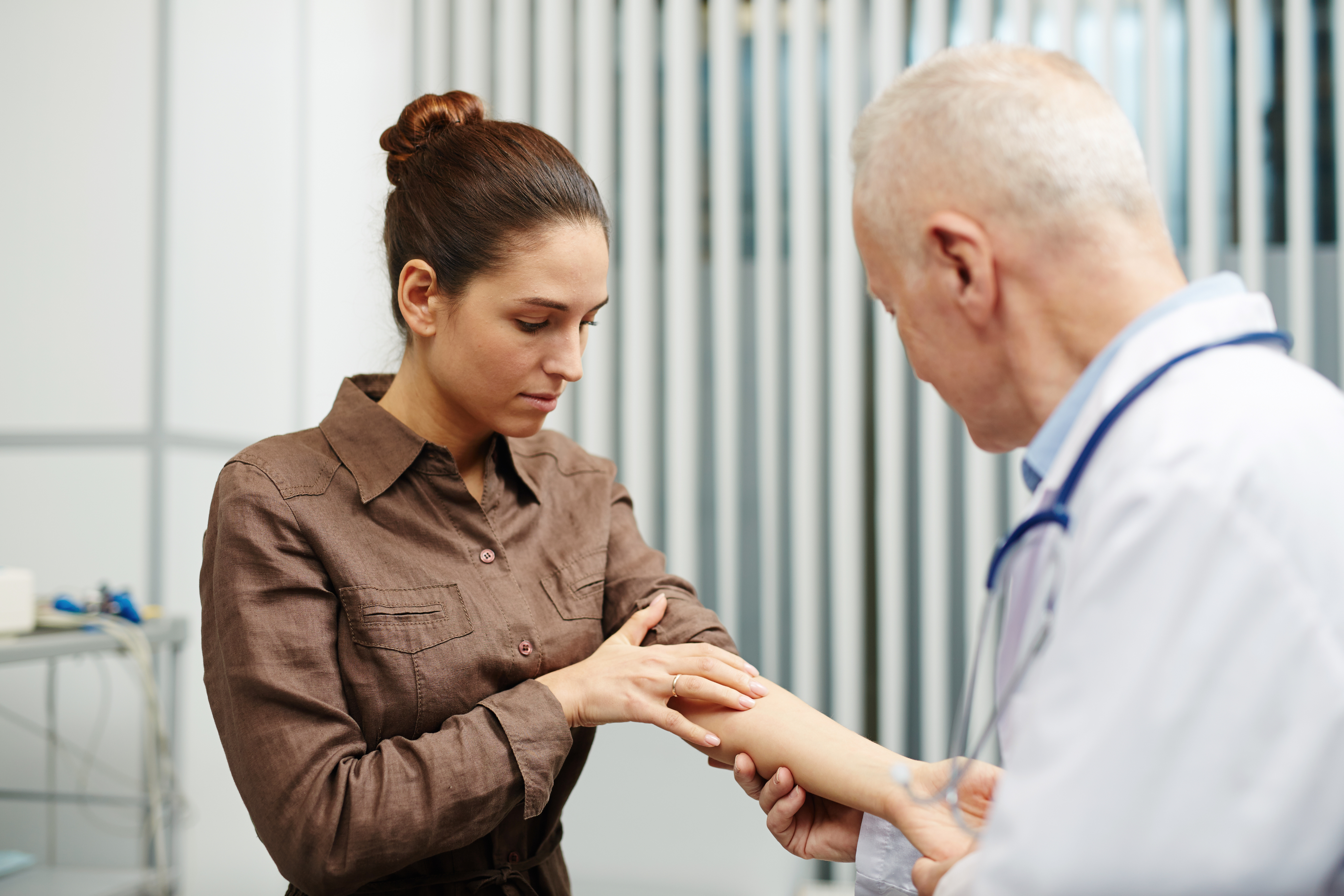 Dermatologist examining woman's arm