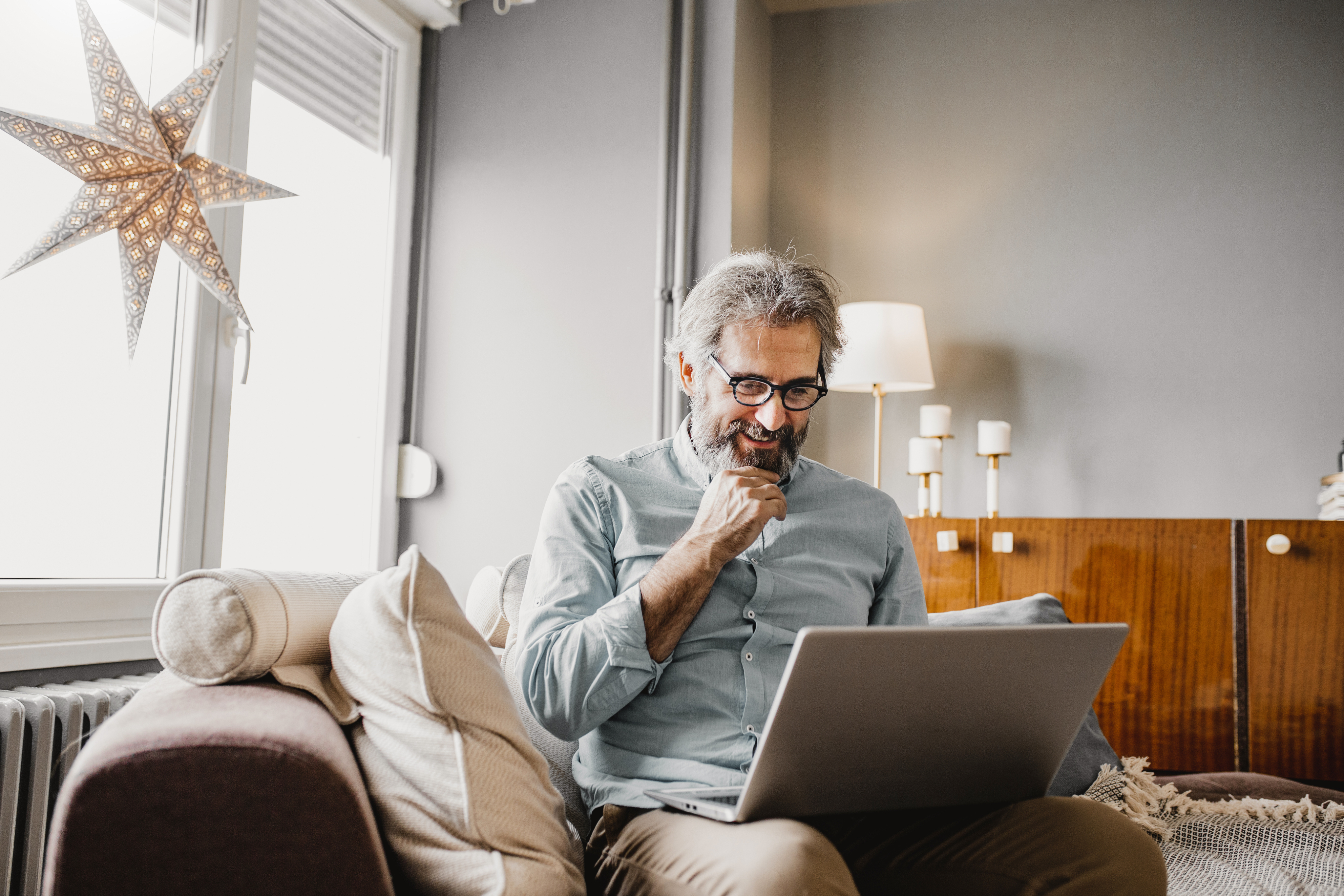 mature man sitting on sofa with laptop