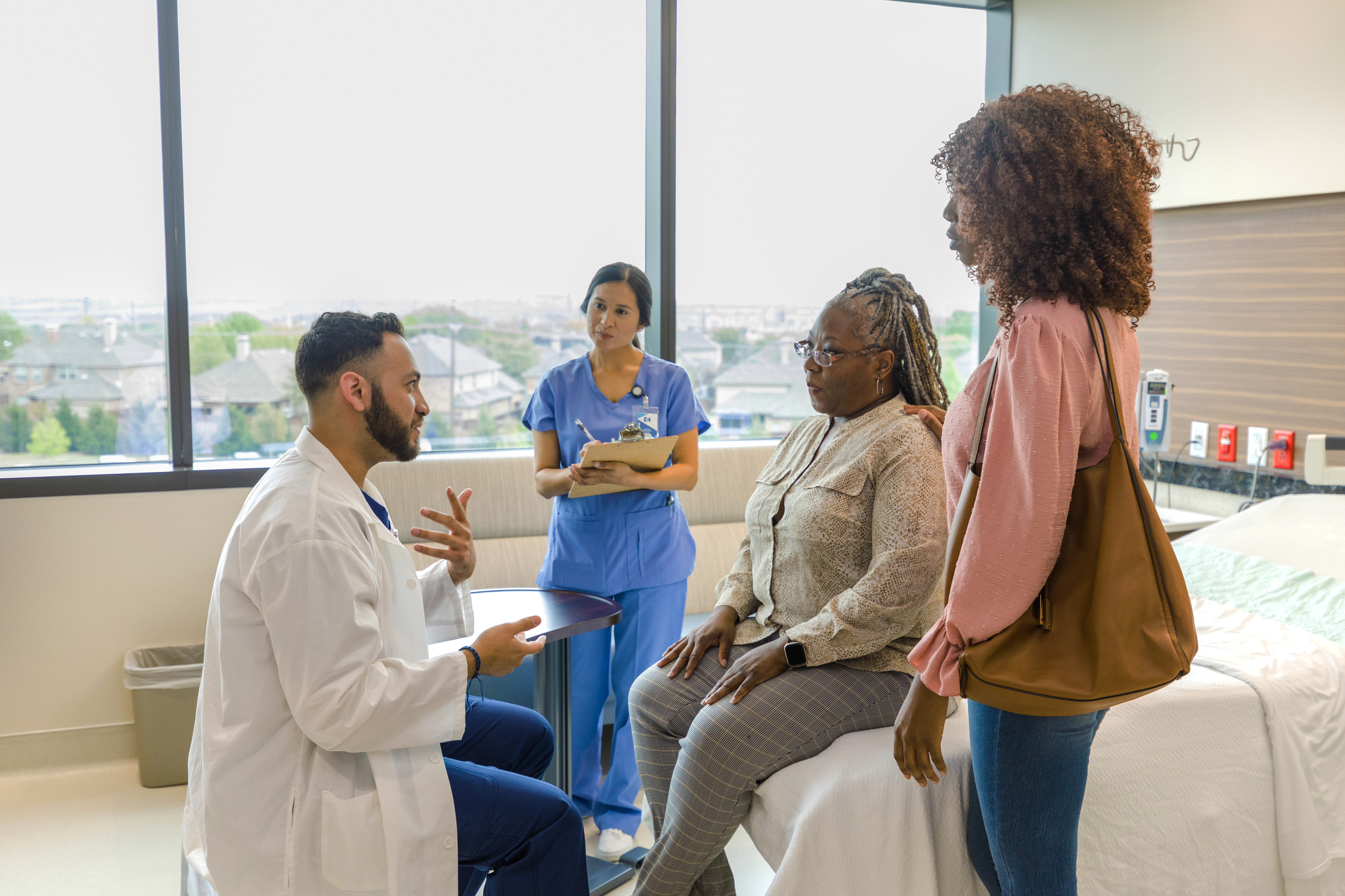 male doctor and female nurse talking to elderly patient and daughter