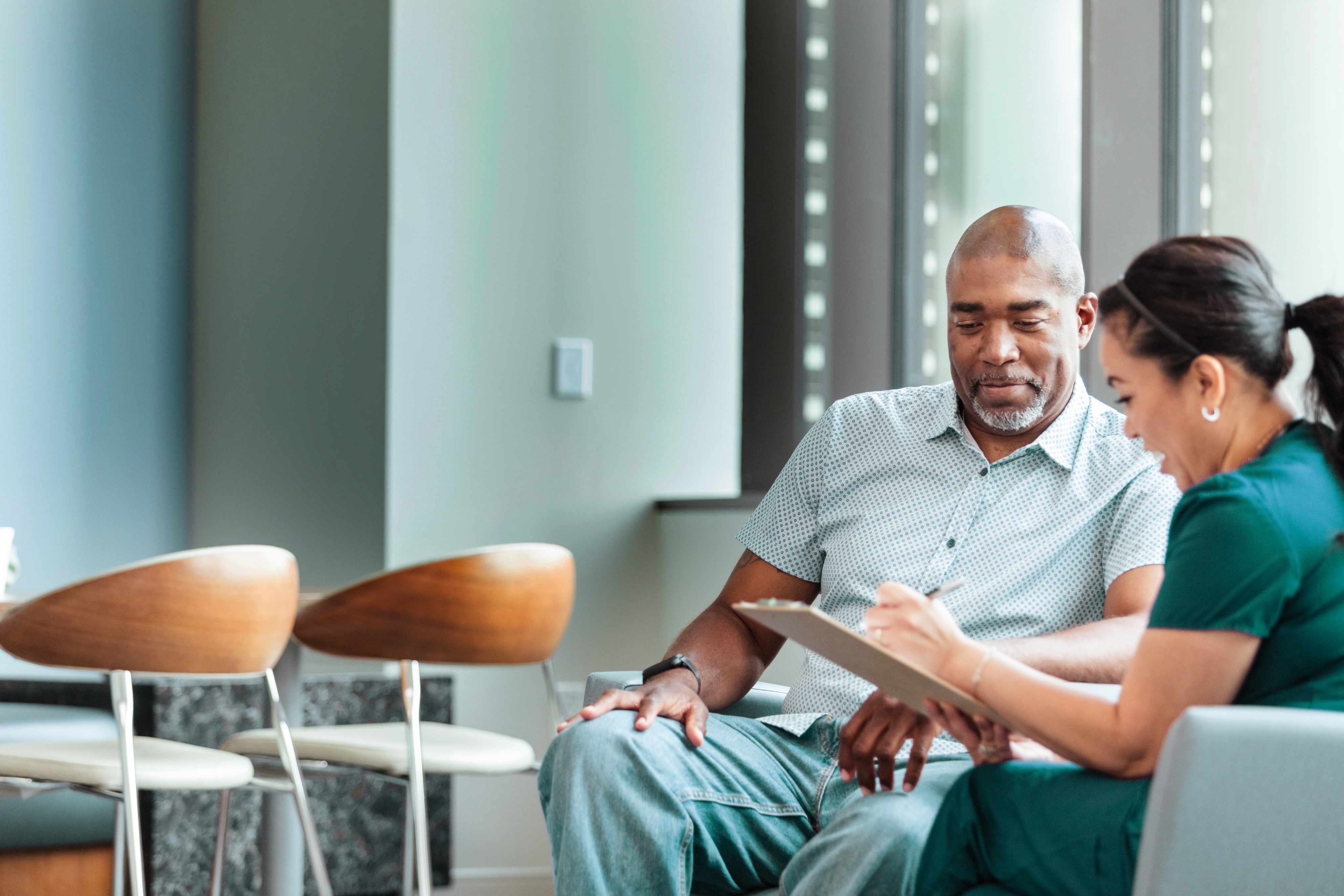 man and woman sitting in chair looking at tablet