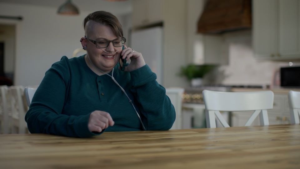 Accredo patient Kira smiles while taking on the phone