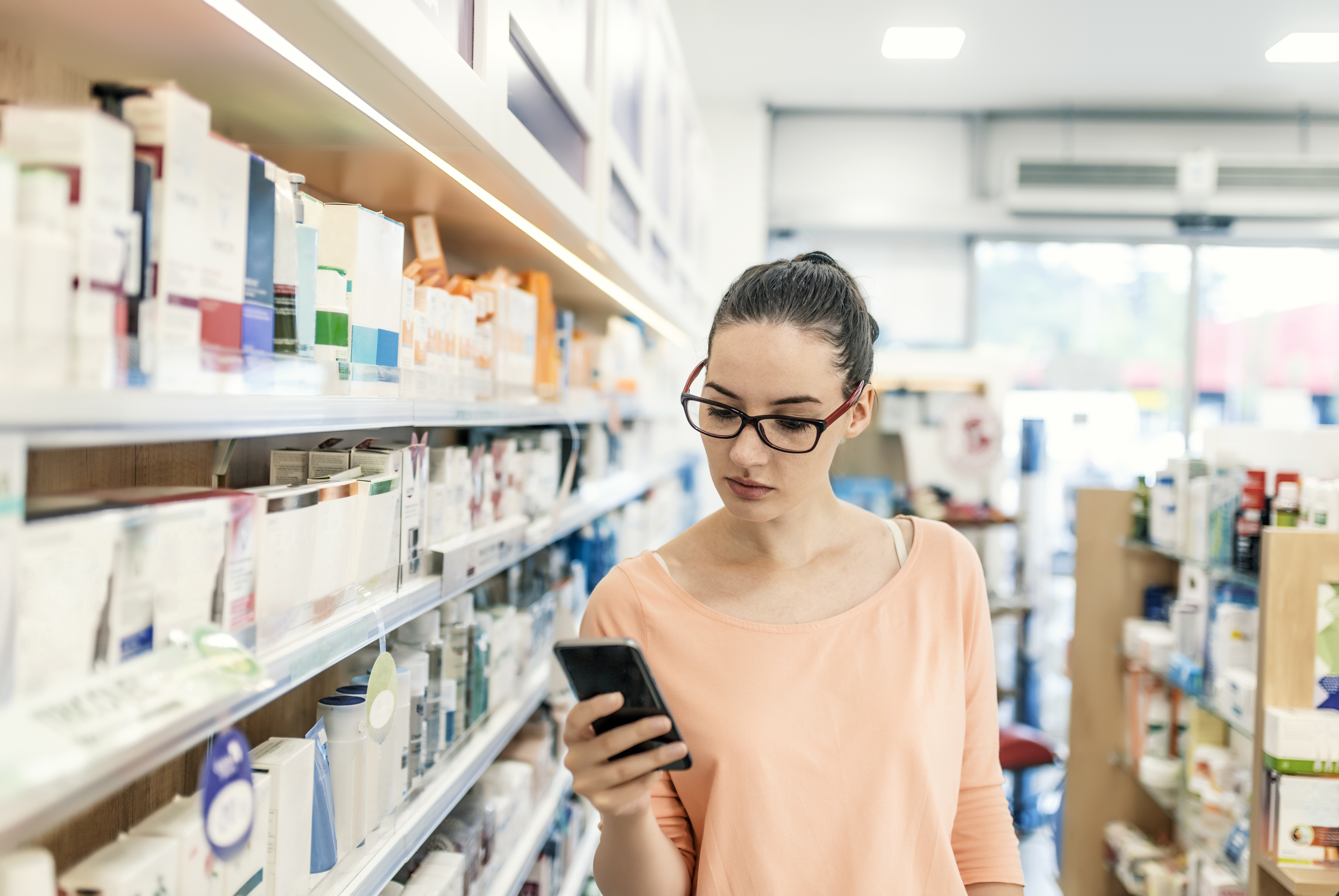 woman holding phone in pharmacy
