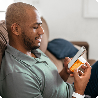 man on couch with pills and phone 