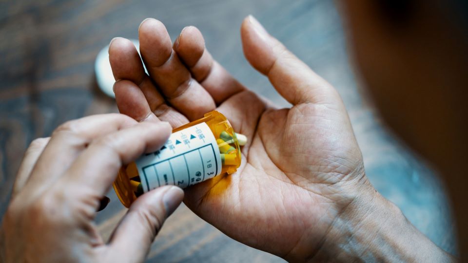 Person opens prescription medication bottle at home