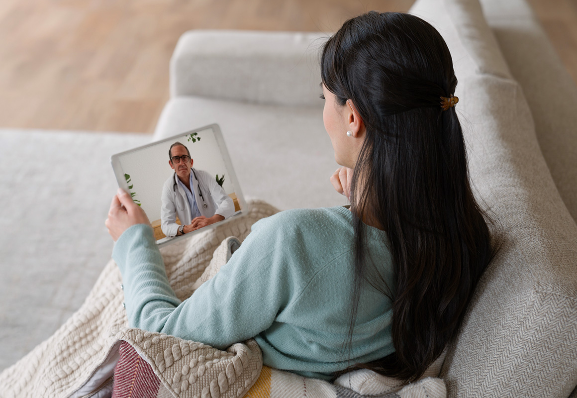 woman on couch with virtual care appointment 