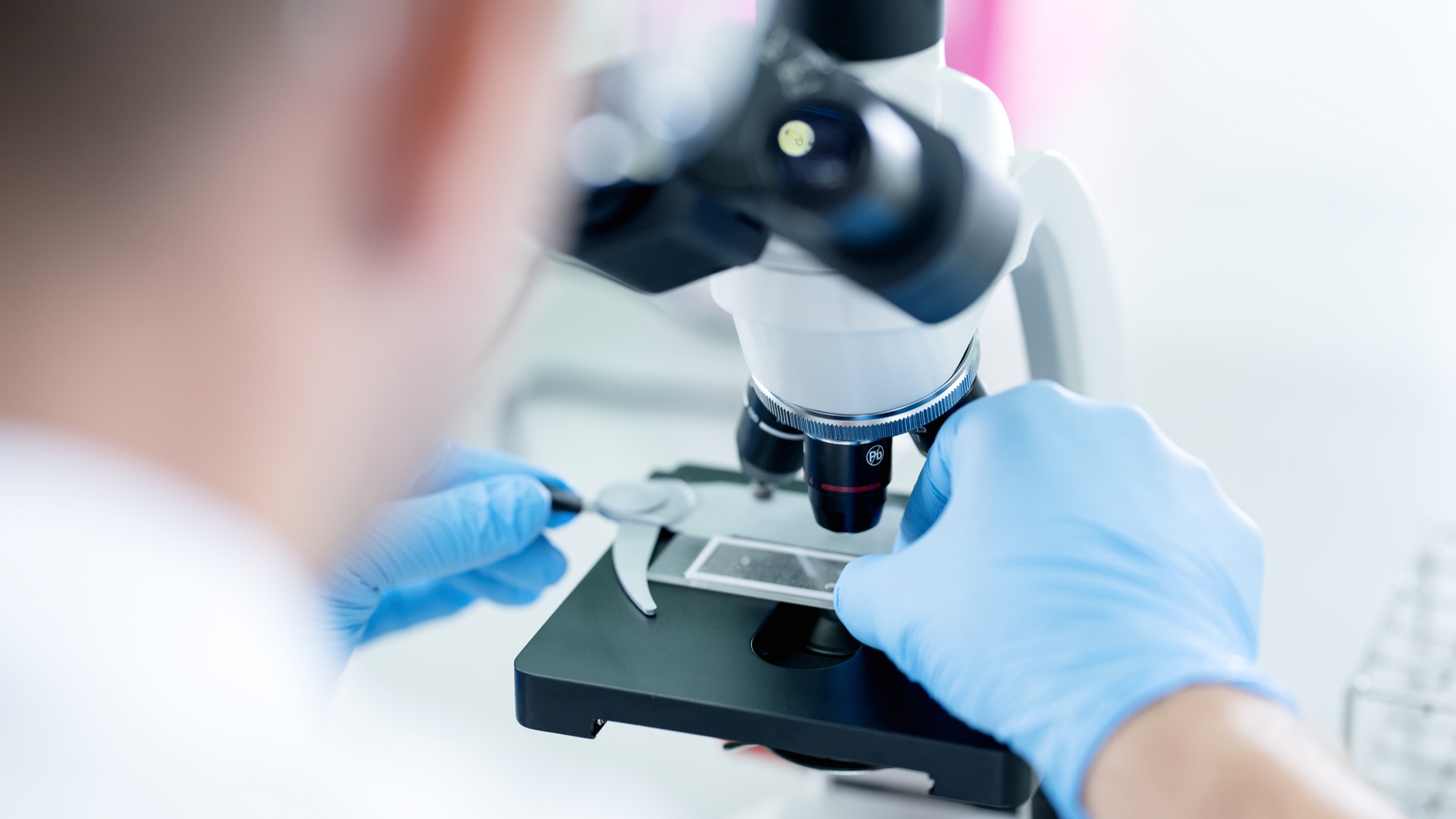 Doctor looks through microscope at cells