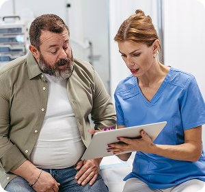 nurse in blue shirt speaking and showing patient items on a clipboard