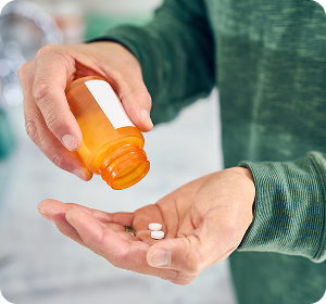 someone pouring two pills out of an orange bottle into their hand