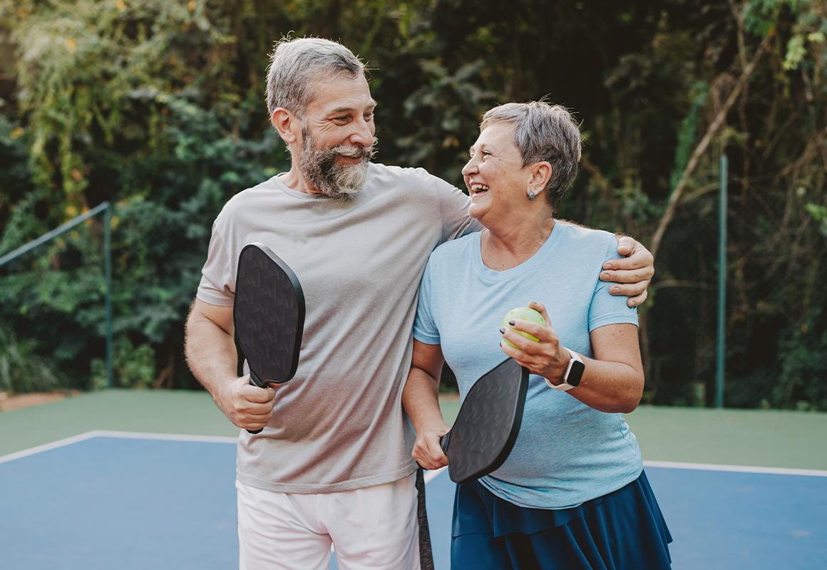 A couple is playing pickleball outside on a court