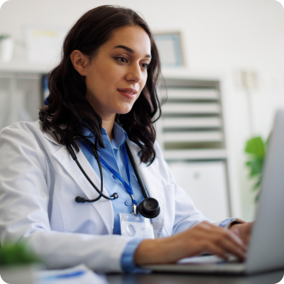 doctor in white coat typing on laptop