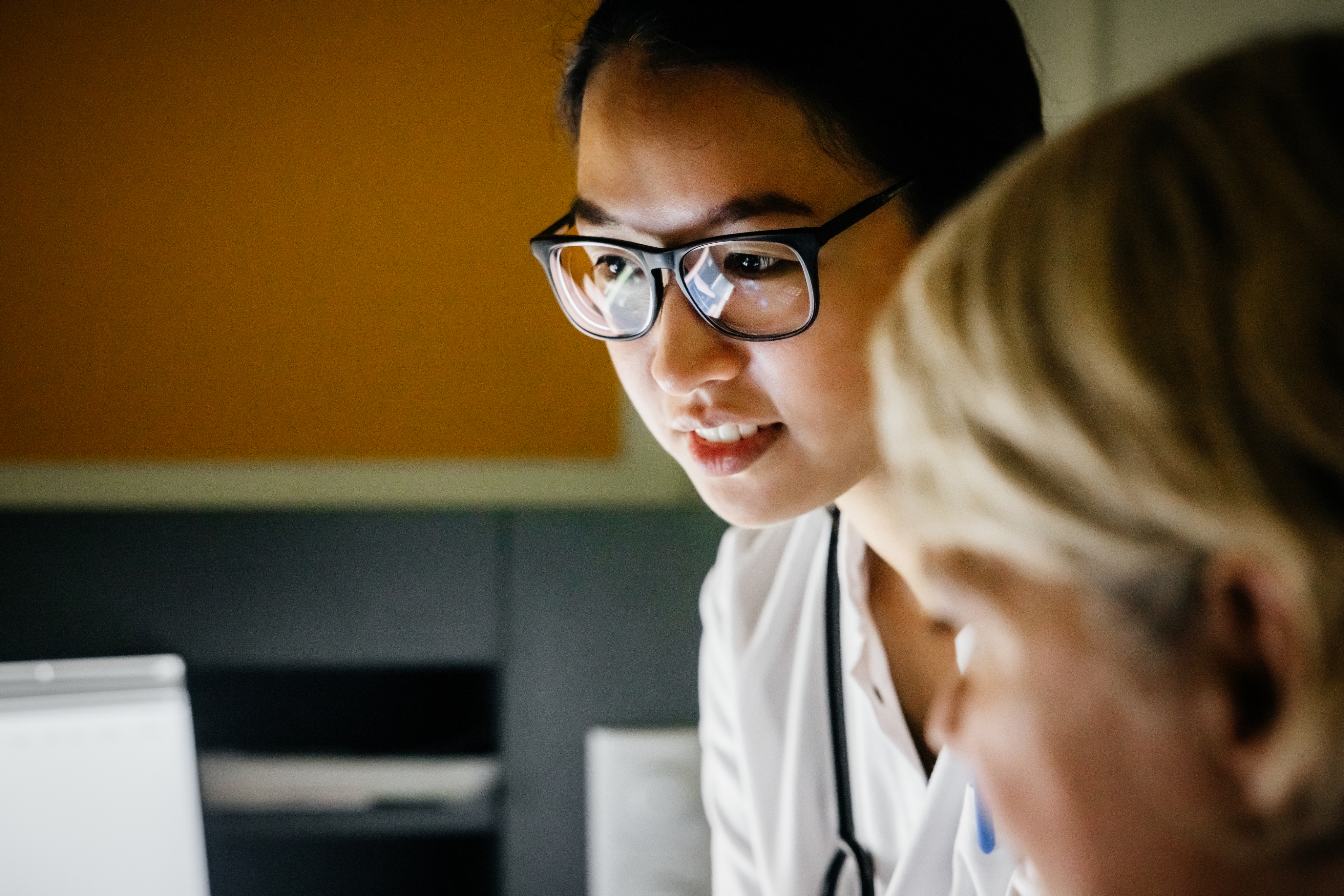 doctor wearing glasses looking at a screen with another person
