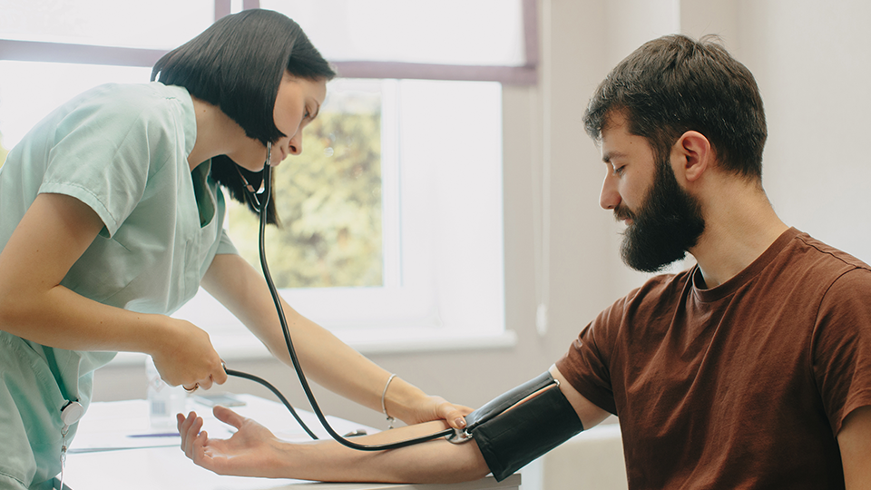 Nurse checking man's blood pressure in clinic