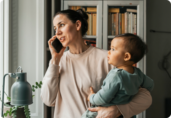woman holding baby while talking on the phone