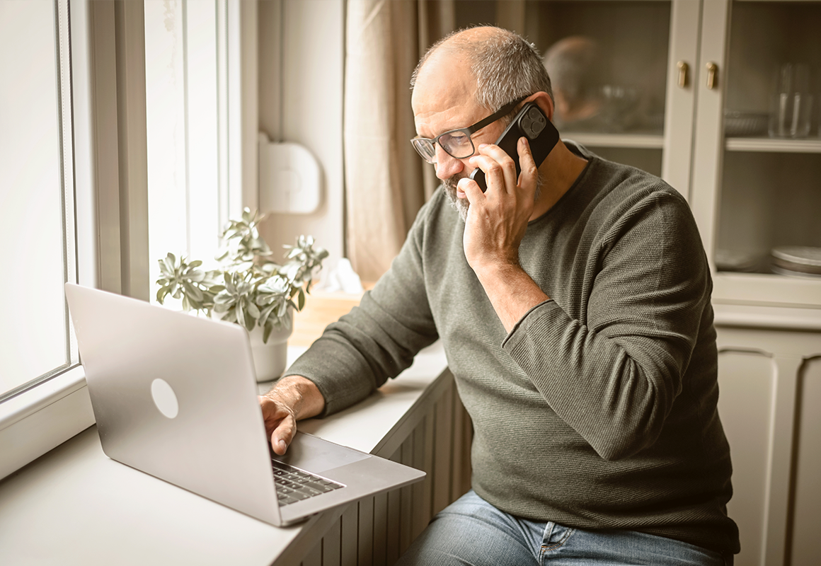 man on his laptop while talking on his cell phone