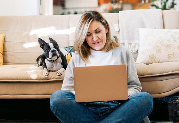 woman on laptop with her dog sitting next to her