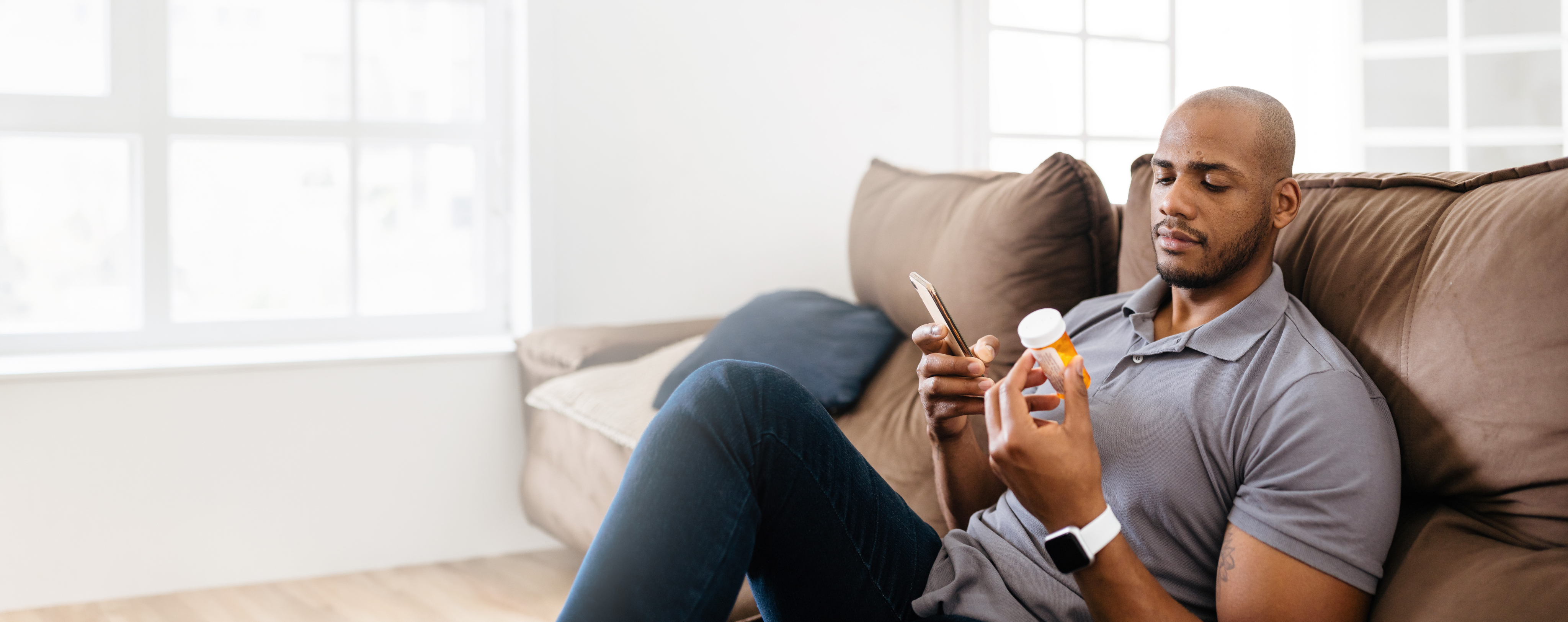 man holding medication while on phone