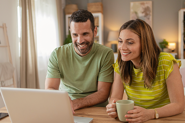 couple smiling while looking at laptop